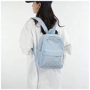 Detail of light blue corduroy backpack featuring ribbed texture and drawstring zippers
