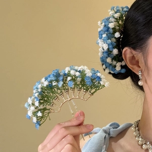 Close-up detail of a gold hair pin with blue and white flowers and elegant styling