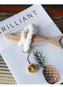 Detail of wooden fish ornament with white cotton rope, golden ring and small brass bell