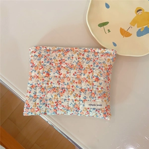 Close-up of a floral quilted cotton makeup bag with 'simple wish' label on a desk