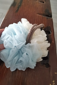 Detail of blue and white dual-tone mesh bath loofah sponge with gray hanging rope