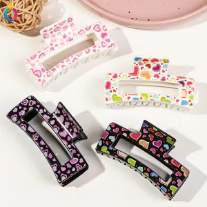Detail view of four large rectangular acrylic hair claws with colorful heart patterns