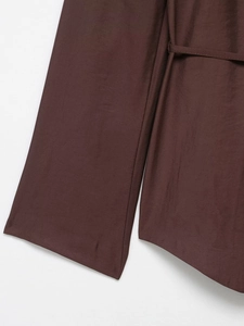 Macro detail of dark brown blazer fabric texture and matching thin waist belt accessory