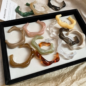 Flat lay of colorful wavy resin acrylic open bangles in diverse vintage finishes