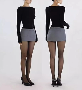 Detailed view of grey bodycon mini skirt paired with long sleeve top and black stockings