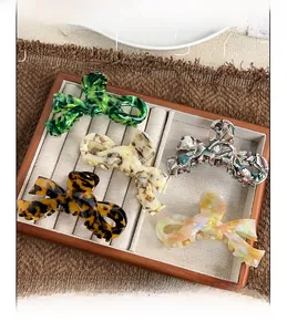Detailed top view of five elegant bow-shaped acetate hair claws in assorted vintage colors