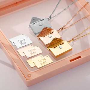 Macro detail of envelope pendant necklace in silver, rose gold and gold finishes