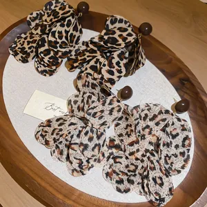 Retro leopard print chiffon flower earrings with brown beads on wooden tray background