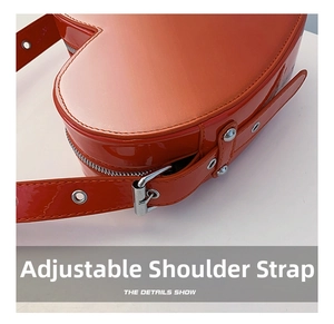 Détail de la bandoulière réglable avec boucle argentée sur un sac en cuir verni brillant