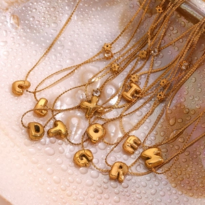 Vue macro des pendentifs lettre bulle dorés 18K avec accents d'étoiles et petit zircon