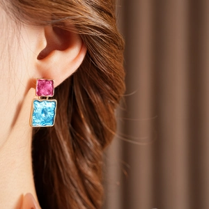 Close-up of square drop earrings with textured gold edges and vibrant oil drip enamel
