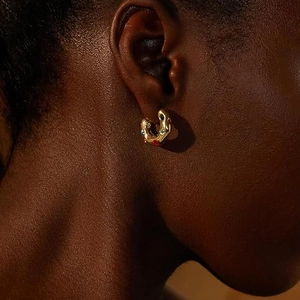 Macro detail of vintage gold textured earring with multi-colored gemstones on model