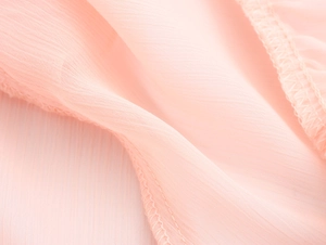 Detailed close-up of pink chiffon fabric texture and high-quality stitching on dress