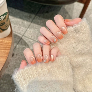 Cat eye press-on nails with orange-pink gradient, leaf rhinestones and soft shimmer
