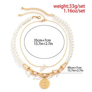 Detail of layered gold chain necklace featuring vintage embossed pendant and pearls