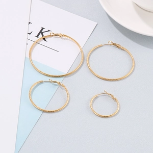 Golden hoop earrings with textured spiral design in four sizes on a minimalist background