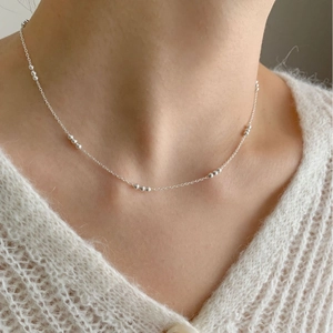 Minimalist 925 sterling silver beaded chain necklace worn by model over a white sweater