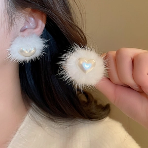 Close-up of fluffy white fur pompom earrings with a pearl heart accent for women