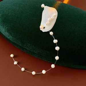 Detailed close-up of natural shell pieces and round white pearls on a minimalist earring