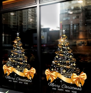 Close-up of golden Christmas tree window sticker with festive lettering on glass surface