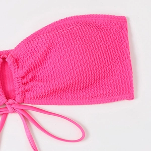 Detail shot of fuchsia smocked bikini top featuring ruched fabric and tie straps