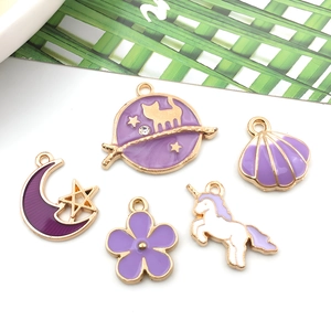 Detailed close-up of purple enamel charms featuring moon, cat, and unicorn shapes
