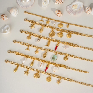 Detail of golden ocean-themed charm bracelets with starfish, seashell, and fish pendants