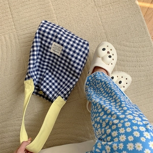 Détail du sac cabas en toile à carreaux bleus avec des bandoulières jaunes contrastées