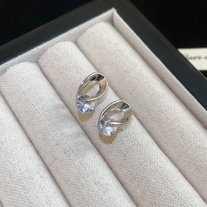 Macro shot of silver hollow drop earrings with round zircon stones in a gray jewelry box