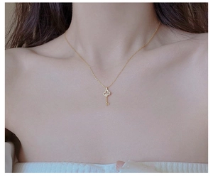 Detailed close-up of a gold-plated S925 sterling silver key pendant necklace on a model