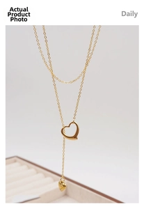 Detail of gold double-layer necklace featuring hollow and solid heart pendants