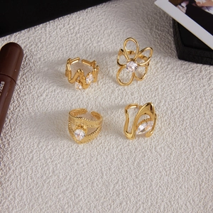 Detalle de cuatro anillos de acero inoxidable dorado con circonitas sobre blanco