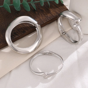 Detailed view of silver spring-loaded bangles on wood and cotton fabric background