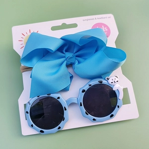 Detail of light blue girls' sunglasses with bear charm and matching bow headband set