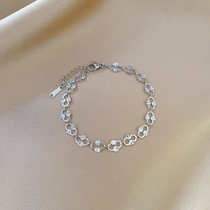 Detailed view of stainless steel pig nose chain bracelet on beige textured fabric