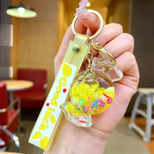 Close-up of yellow candy liquid keychain with glitter stars and Good Luck strap