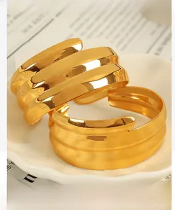 Detail view of gold-plated wave pattern open bangles on a decorative white plate