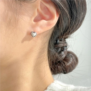 Close-up of a silver twist-edge heart stud earring worn on a model ear lobe