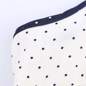 Gros plan sur tissu blanc à pois avec bordure bleue et détails de couture