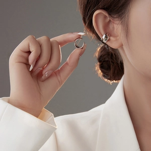 Minimalist silver ear cuff with beaded edges shown on ear and held by hand