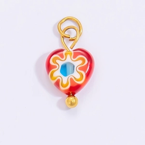 Macro detail of heart-shaped red art glass pendant with blue wave patterns and gold accents