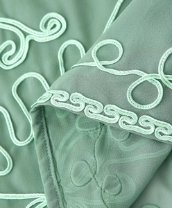 Detailed close-up of mint green silk fabric featuring intricate cord embroidery