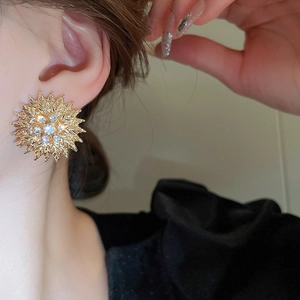 Boucles d'oreilles tournesol dorées avec cristaux portées pour un look de luxe chic