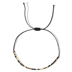Adjustable Morse code braided rope bracelet with black and gold seed beads on white background