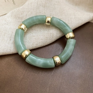 Close-up of iridescent acrylic bead bracelet with gold metal accents and elastic cord
