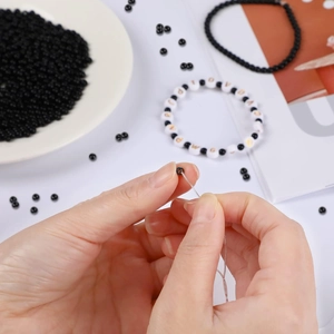 Close-up of crafting handmade jewelry with gold spacing beads and letter charms