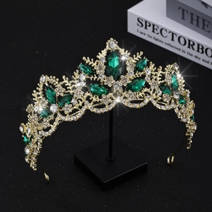 Macro detail of luxury gold bridal crown with white rhinestones and emerald green crystals