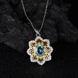 Macro shot of oval blue gemstone pendant with golden honeycomb frame and white zircons