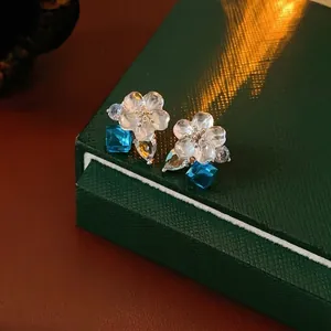 Elegant floral drop earrings with blue cubic zirconia stones on silver studs display