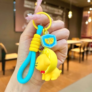 Close-up of yellow puppy keychain with blue braided rope and lemon charm decoration